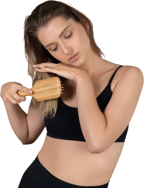 Front view of a young woman brushing her hair tips