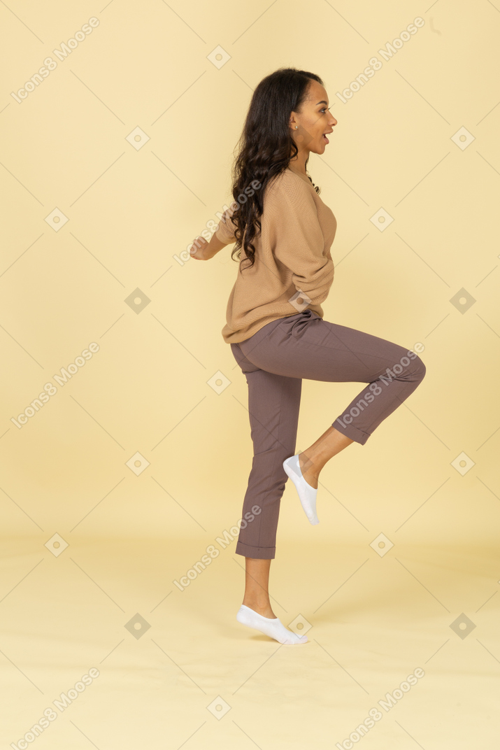 行進する浅黒い肌の若い女性の脚を上げる側面図