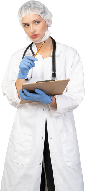 Vista frontal de una joven doctora sosteniendo una tableta y apuntando a un lado