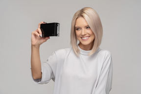 Lächelnde junge frau, die ein selfie mit einer alten kamera nimmt