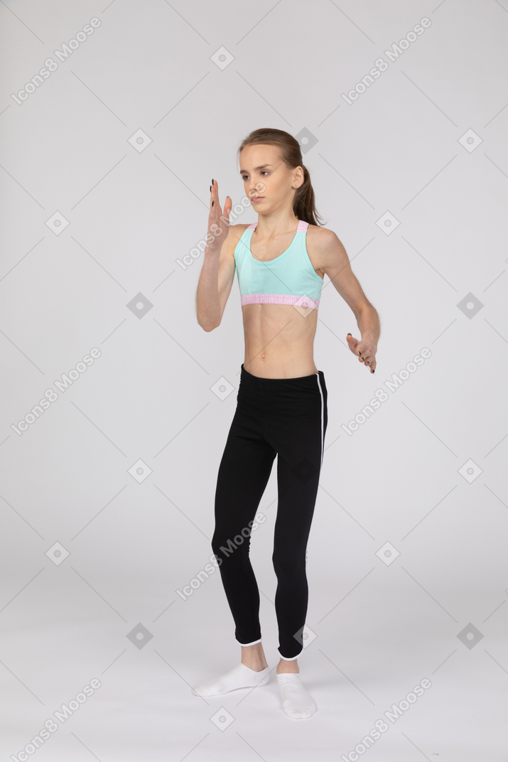 Three-quarter view of a teen girl in sportswear standing like a robot