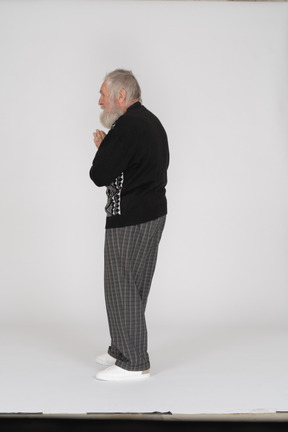 Side view of an elderly man standing with folded hands