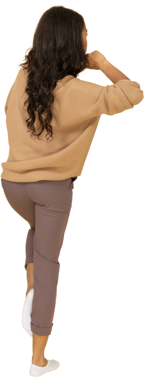 Вид сзади в три четверти темнокожей молодой женщины, касающейся шеи, поднимая ногу