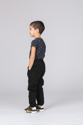 Vista lateral de um menino em roupas casuais em pé com as mãos nos bolsos