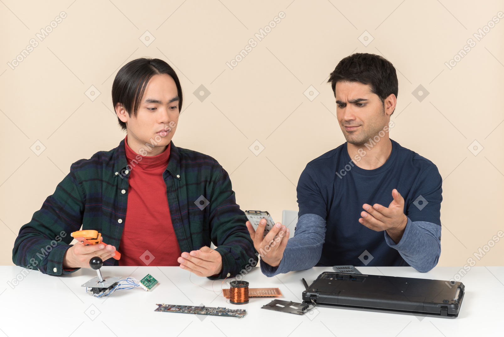 Two young geeks sitting at the table and fixing laptop