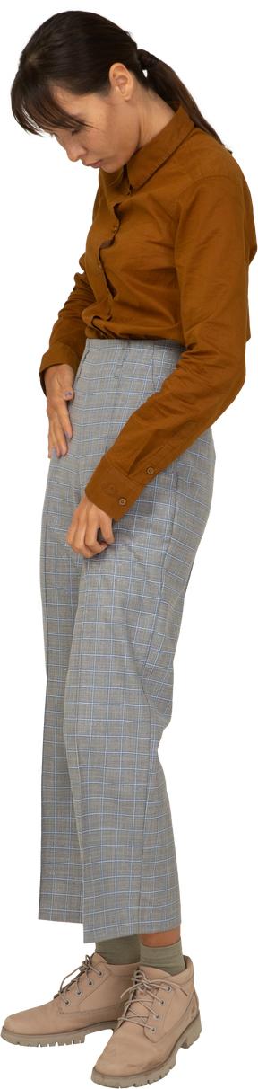 Vue latérale d'une jeune femme asiatique en culotte et chemisier mettant les mains dans les poches