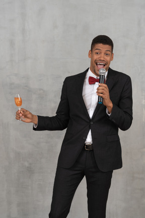 Homem com microfone e taça de champanhe rindo