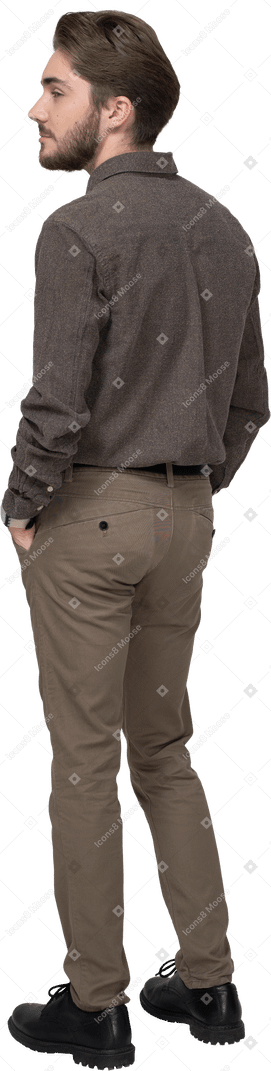 Three-quarter back view of a man in casual clothing putting hands in pocket