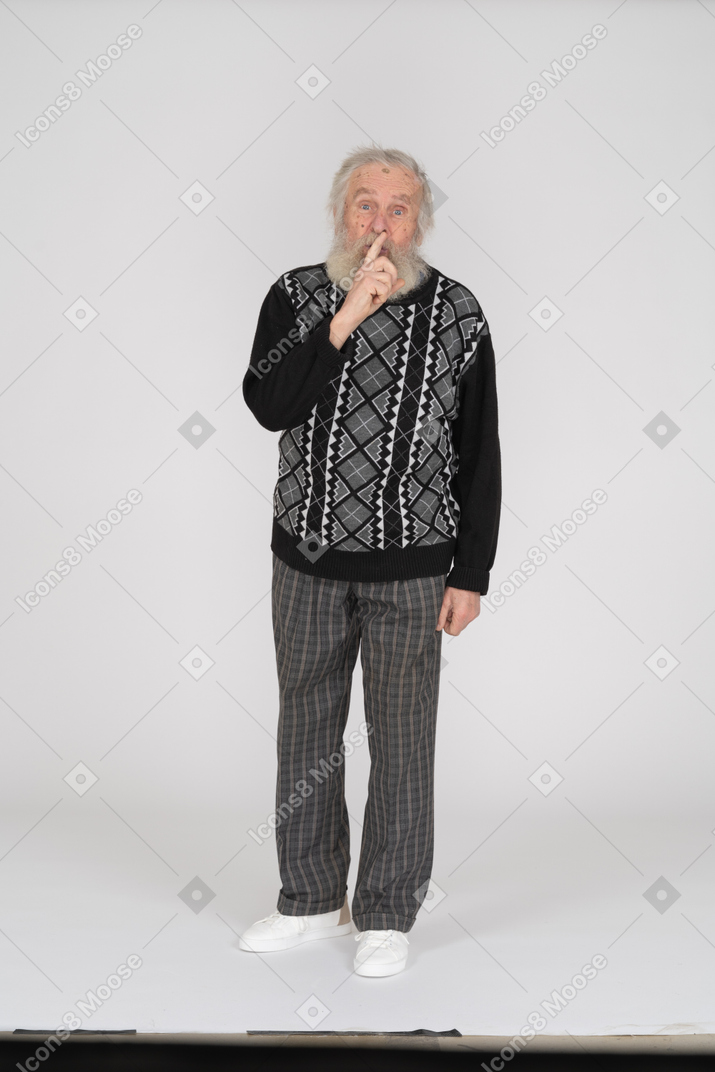 Old man with finger on lips showing silence gesture