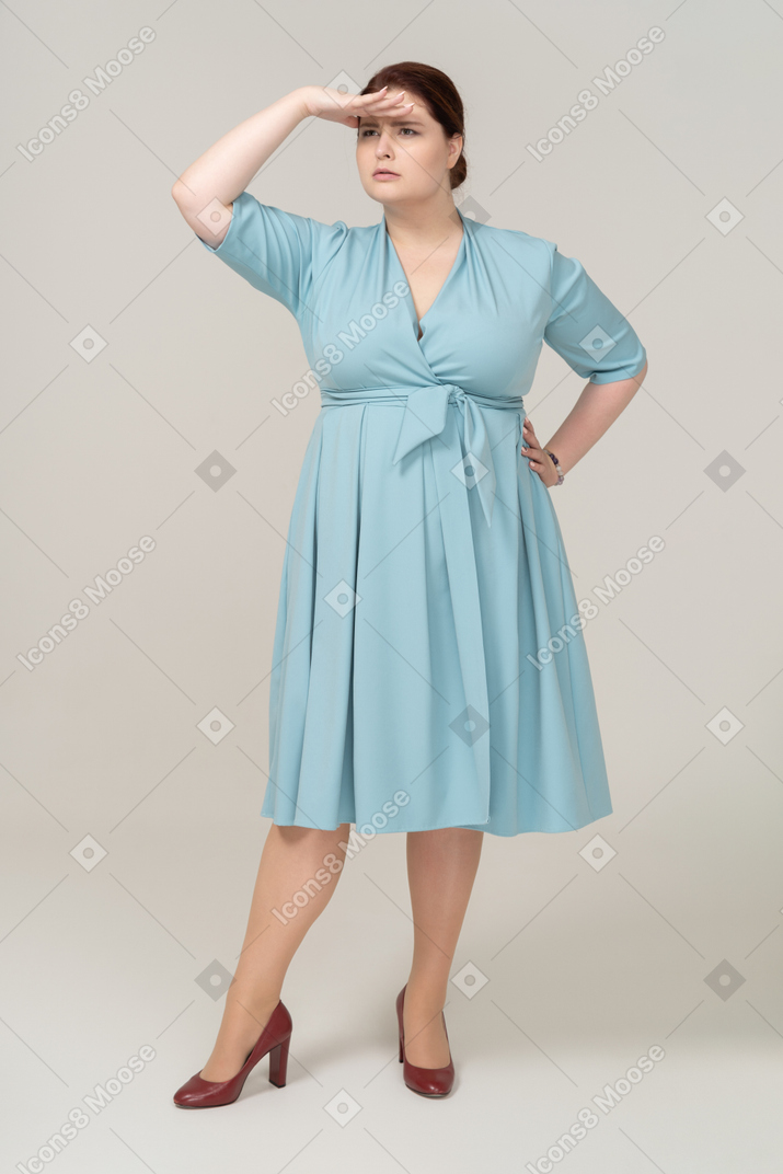 Vista frontal de uma mulher de vestido azul procurando por alguém