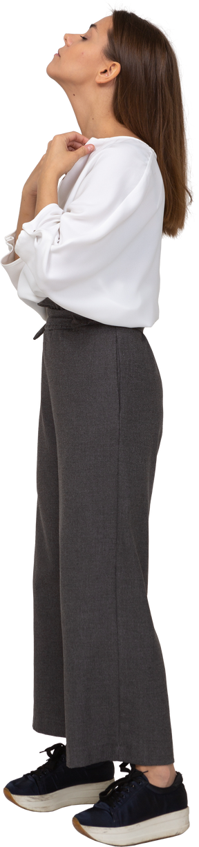 Vista lateral de uma jovem com roupa de escritório ajustando a blusa