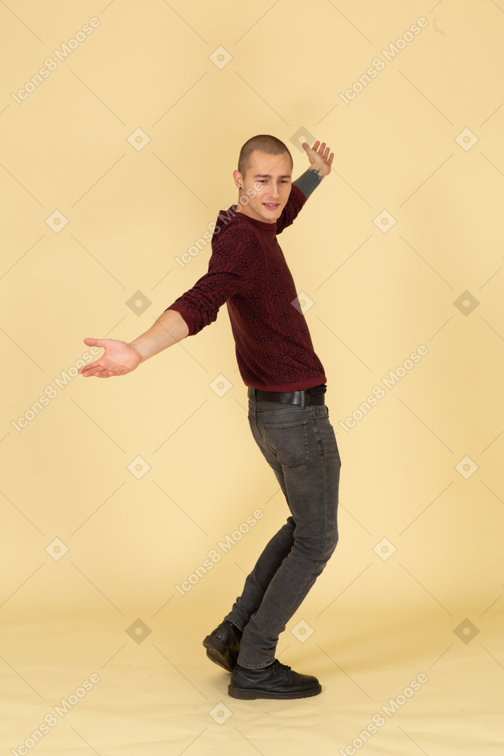 Vue latérale d'un jeune homme en pull rouge levant les bras