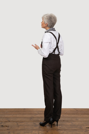 Three-quarter view of an old lady in office clothing raising her hands