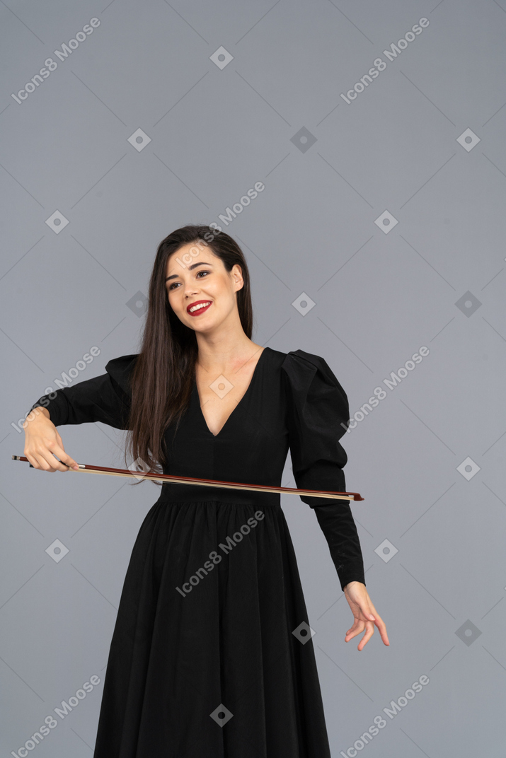 Front view of a pleased young lady in black dress holding the bow