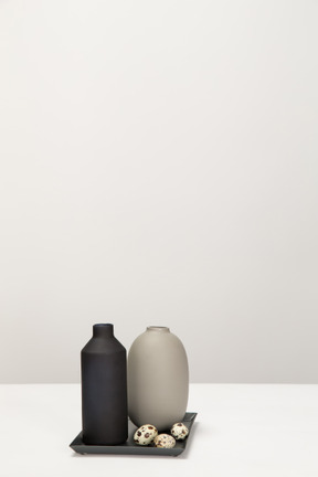 Vases noir et gris et oeufs de caille sur le plateau noir