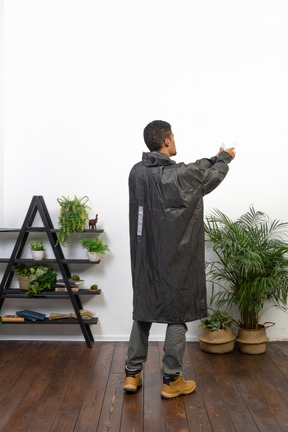 Back view of a man in raincoat holding a cup