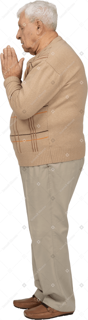 Vista lateral de un anciano con ropa informal rezando