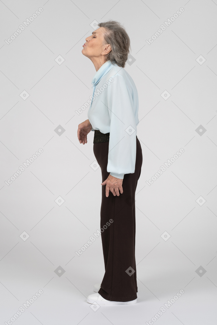 Vista lateral de una anciana haciendo cara de besos