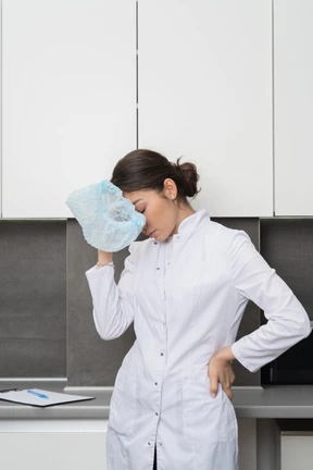 Vista frontal de una doctora cansada tocando la cabeza