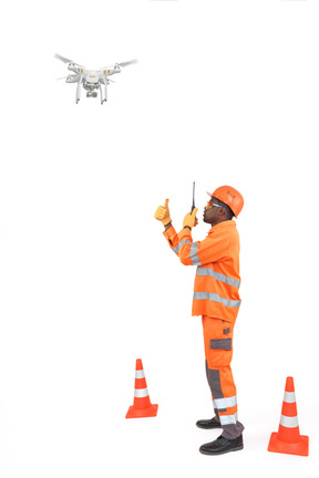 Operaio edile con radio guardando un drone e mostrando pollice alzato