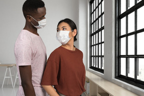 A man and a woman wearing face masks and looking at each other