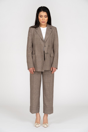 Front view of a young lady in brown business suit looking down