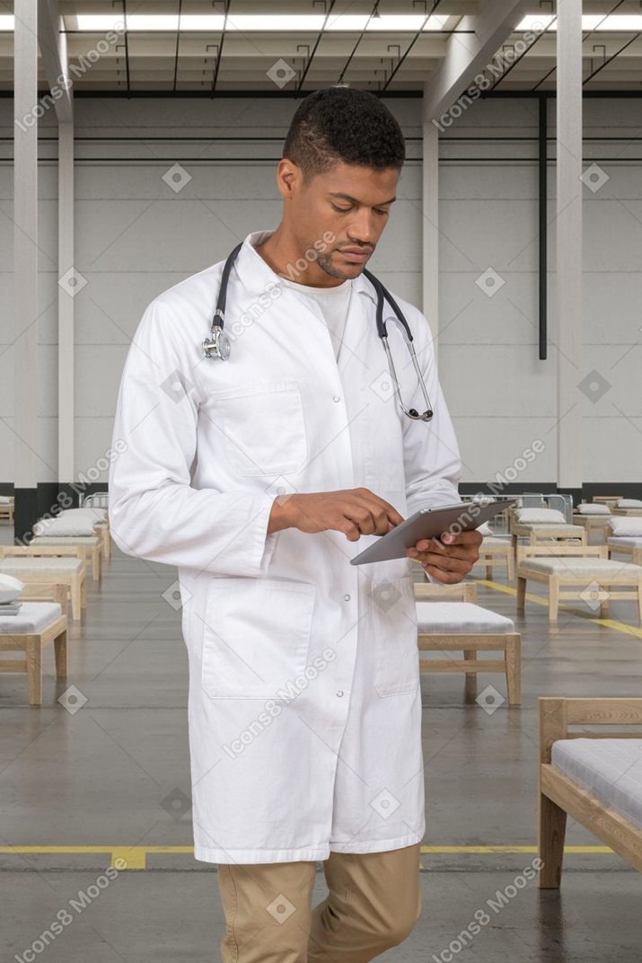 A man in a white lab coat looking at a tablet