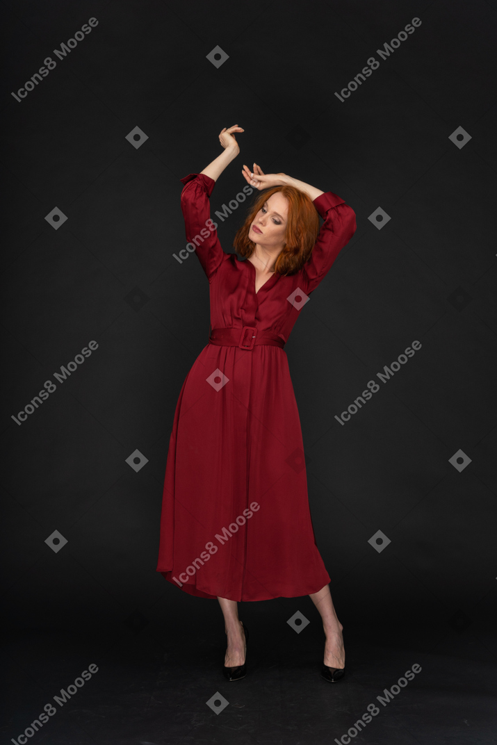 Young ginger lady in red dress spreading arms