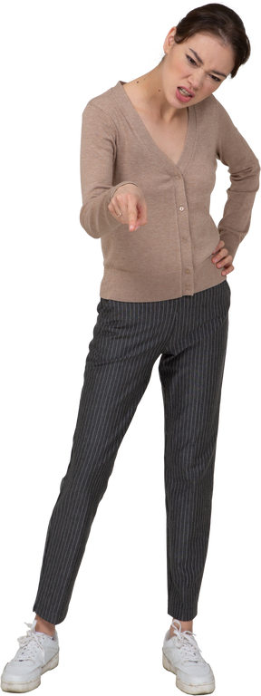 Вид спереди разъяренной барышни в бежевом свитере с указательным пальцем