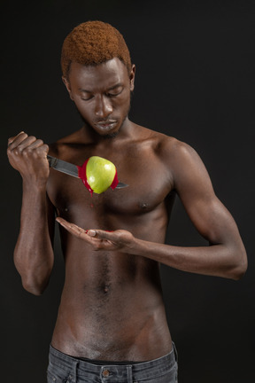 Close-up a young man hurting apple with a knife and watching ketchup pouring out of it