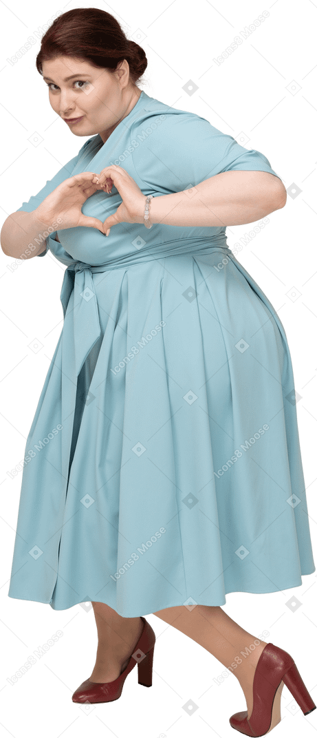 Вид сбоку женщины в синем платье, показывающей жест сердца