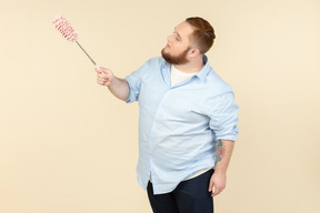 Young overweight househusband holding pipe-cleaner