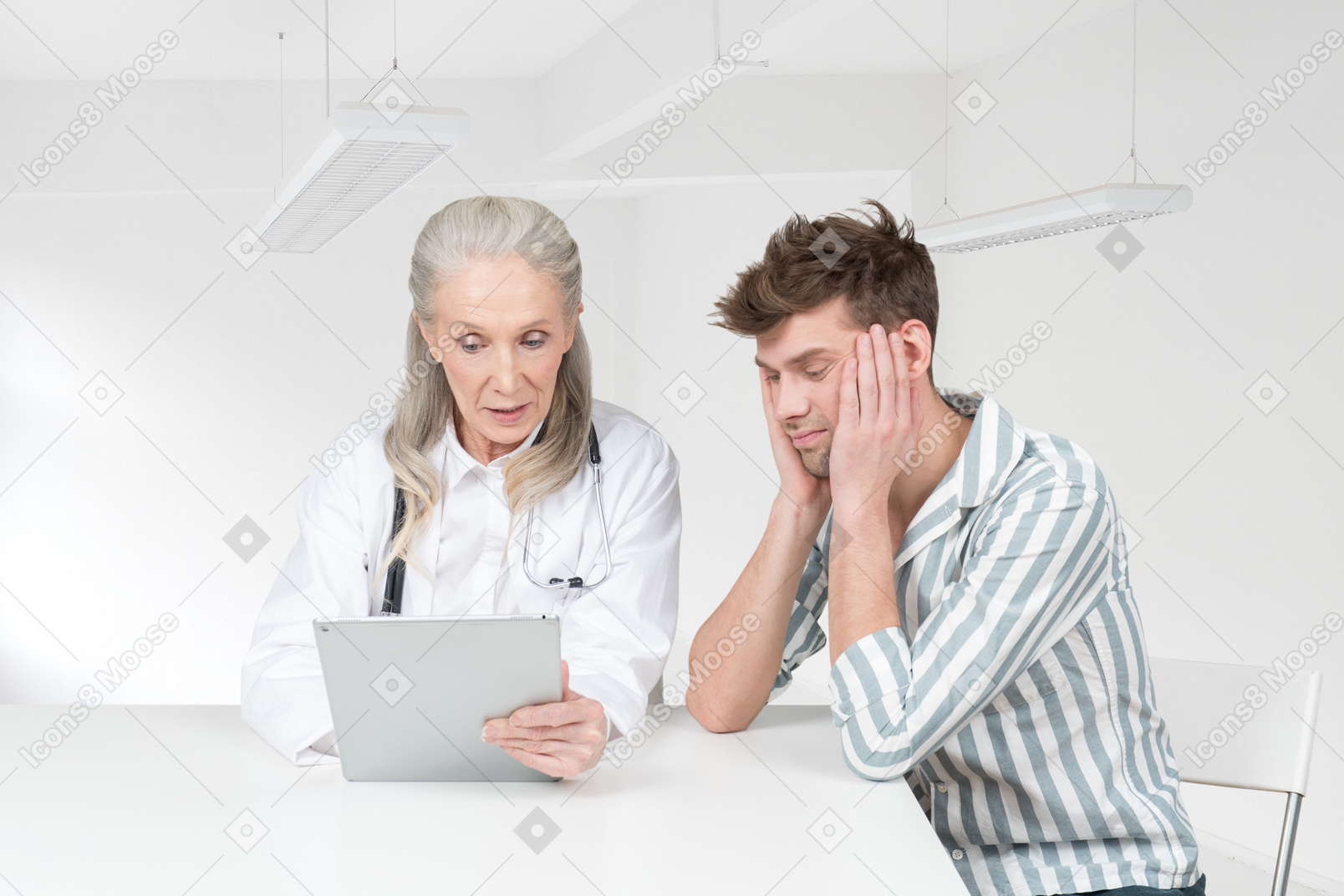 A female doctor using tablet and sitting next to a male patient