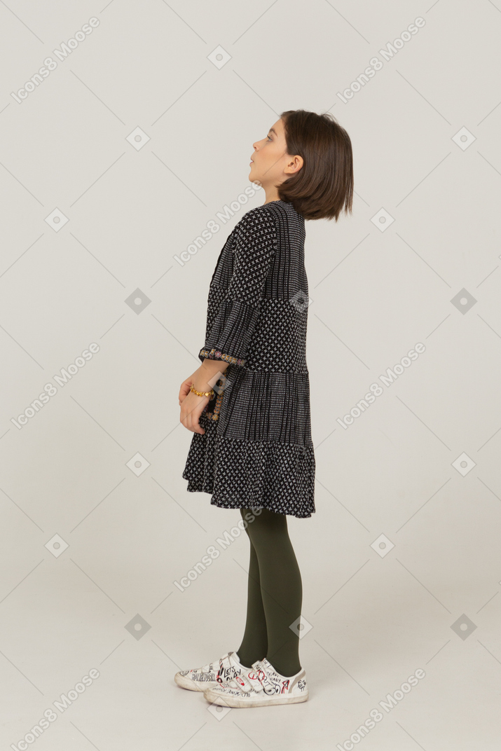 Vista lateral de uma menina confusa em um vestido inclinado para trás