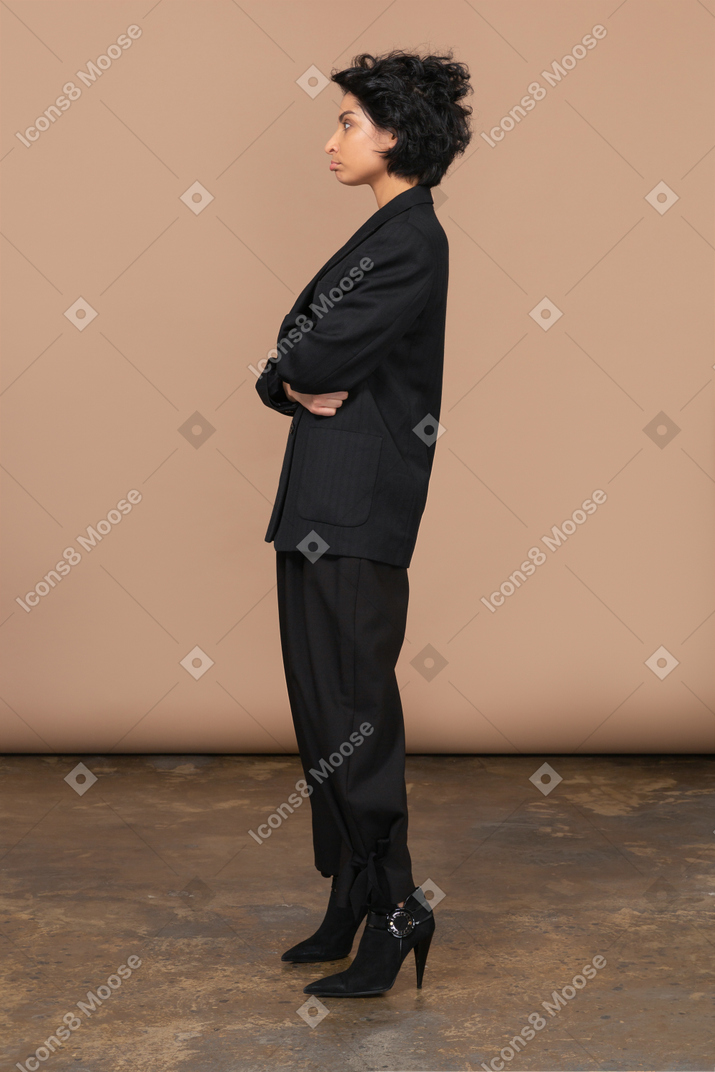 Вид сбоку надутой бизнесвумен, одетой в черный костюм