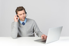 Agente de call center trabajando en la computadora con los ojos cerrados