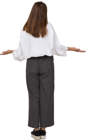 腕を広げているオフィス服の若い女性の背面図
