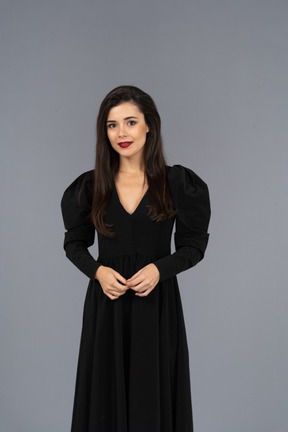 Front view of a smiling young lady in a black dress standing still