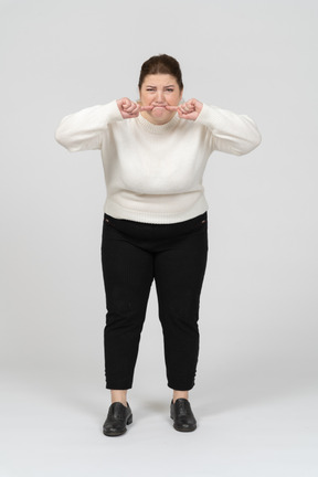 Mujer regordeta en suéter blanco haciendo muecas
