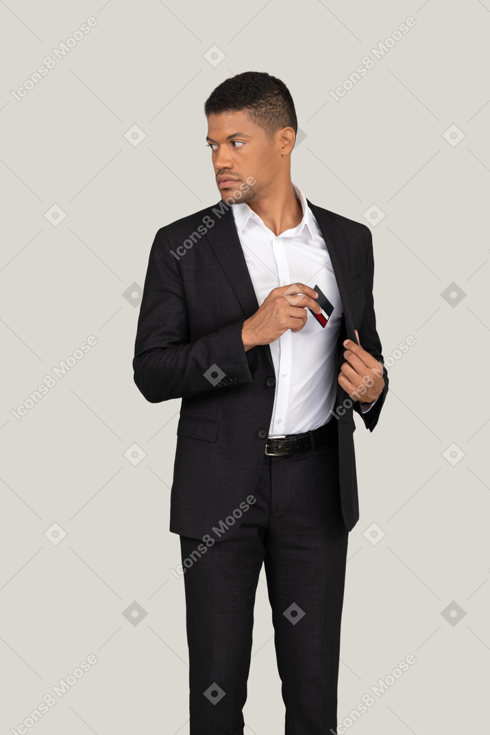 Vista frontal de um jovem de terno preto segurando o cartão do banco