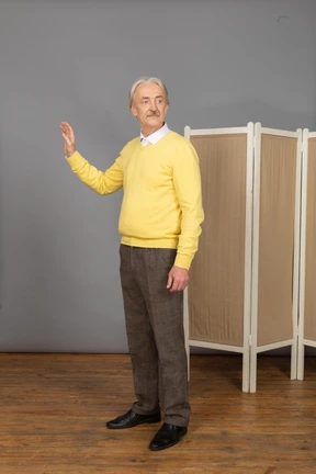 Three-quarter view of an old man raising his hand