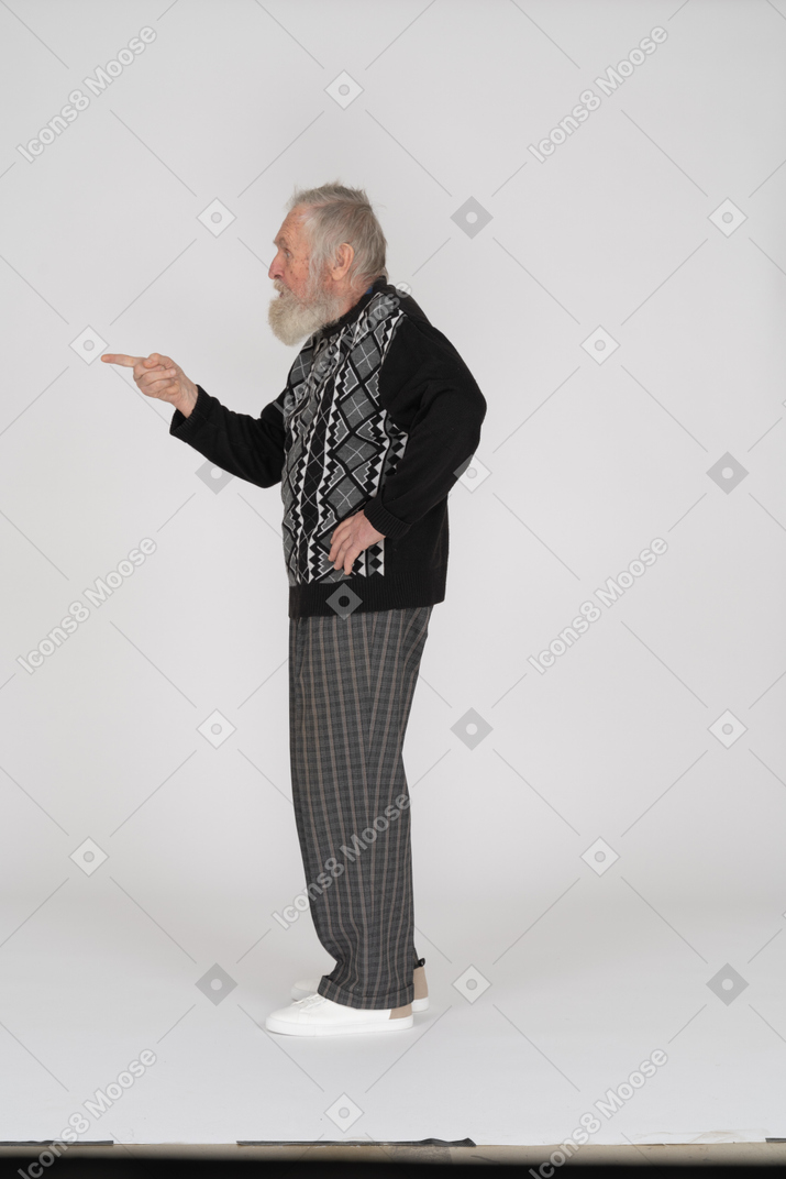 Side view of an old man pointing with his finger to the left