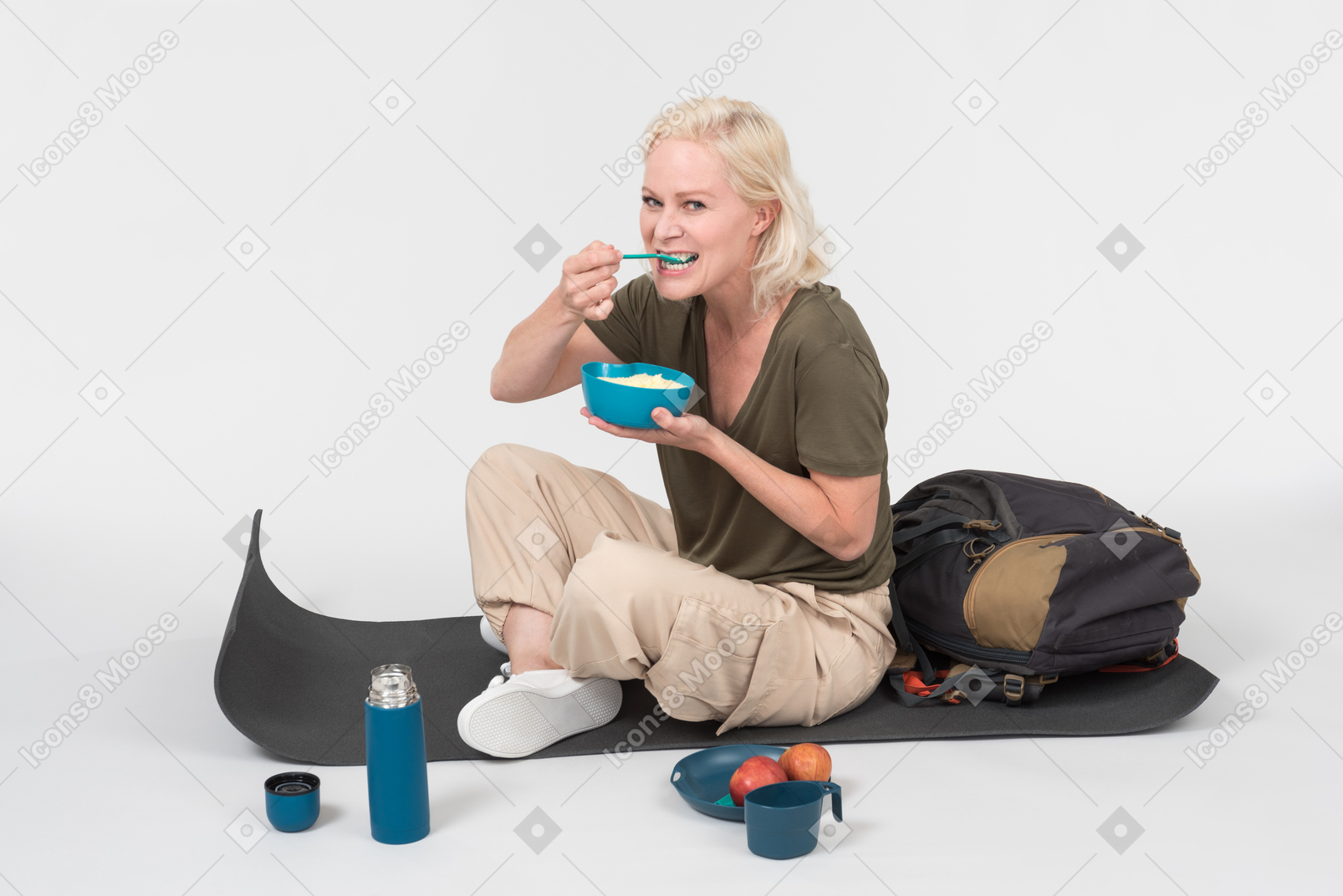 Mature female tourist sitting on tourist mat and eating