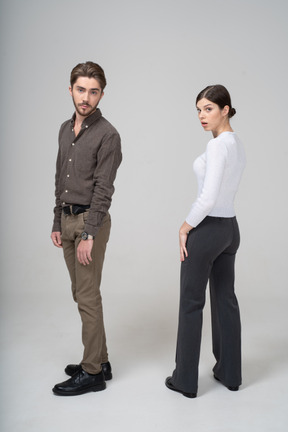 Vista lateral de um jovem casal surpreso em roupas de escritório se afastando