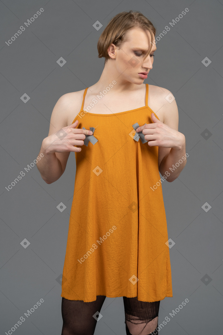 Young non-binary person in orange dress touching chest