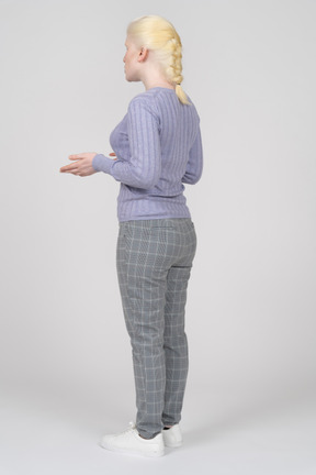Three-quarter back view of a young woman explaining something