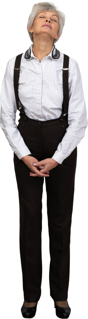 Front view of an old tired female in office clothes grimacing holding hands together