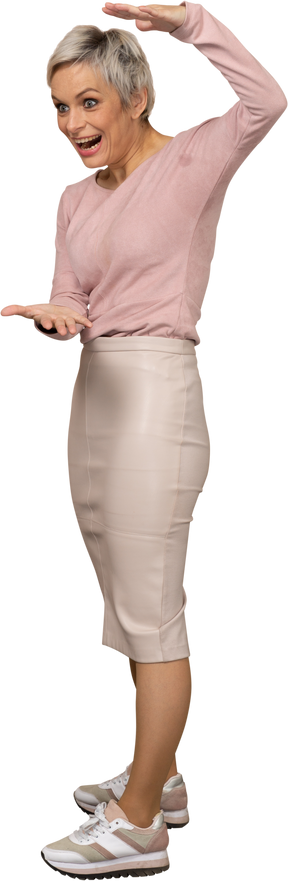 Vista laterale di una donna in abiti casual che mostra le dimensioni di qualcosa