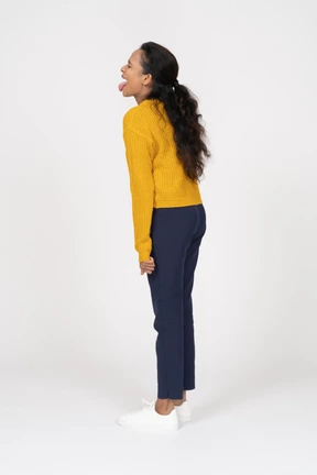Side view of a happy girl in casual clothes showing tongue
