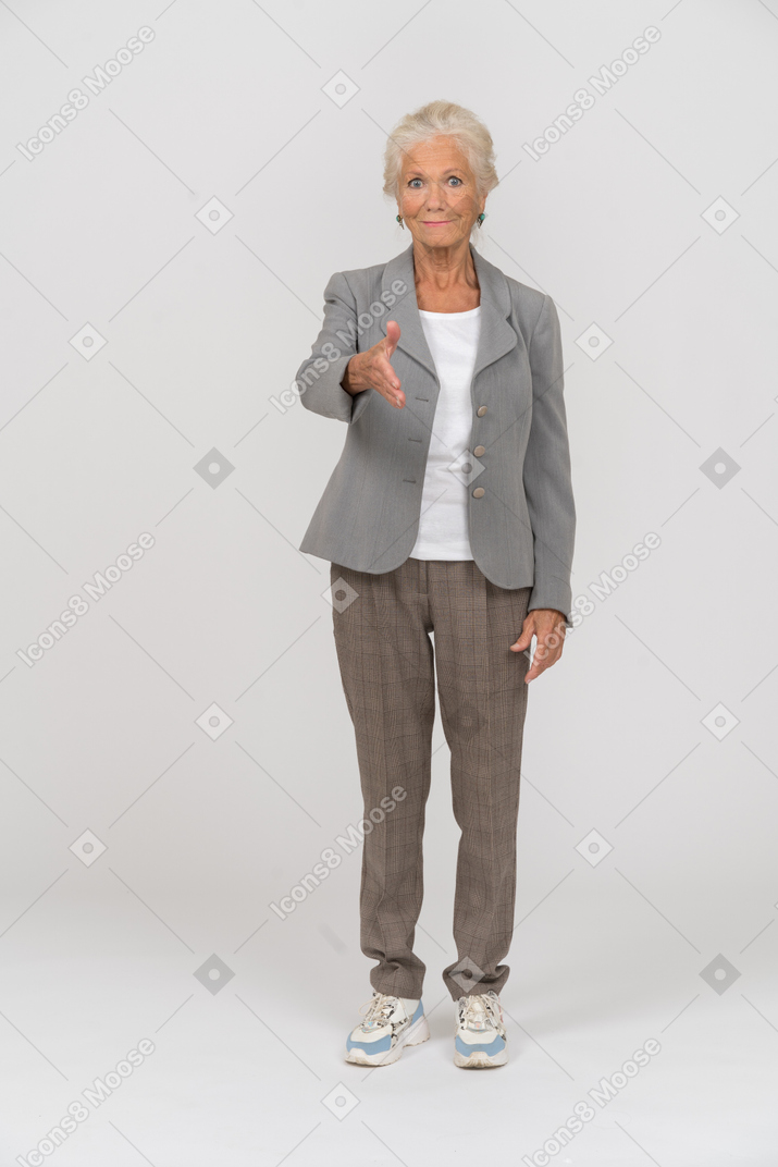 Vista frontal de uma senhora idosa de terno dando uma mão para apertar